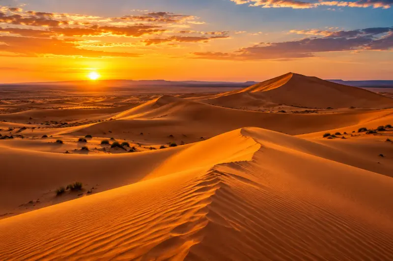 كثبان مرزوكة الذهبية تحت سماء مضيئة عند غروب الشمس